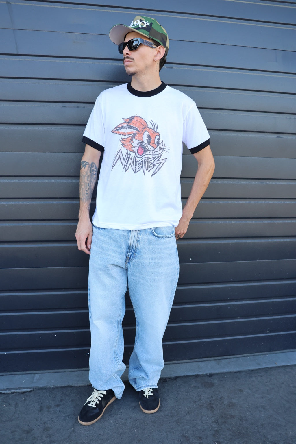 Model wearing the NINETIES rabbit ringer tee in front of a dark garage door